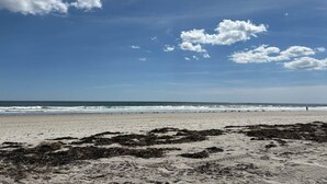 A beach with waves, a clear sky, and seaweed on the sand. - Sunset Sanctuary by Wells Beach (Wells)