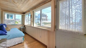 A bedroom with a bed, a nightstand, and a window with a view of houses. - Sunset Sanctuary by Wells Beach (Wells)