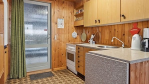 A compact kitchen with wooden cabinets, a built-in oven, a sink, and a small countertop. - 4 Star Holiday Home in Sydals (Sydals)