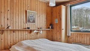 A wooden-paneled room with a bed, a shelf with items, a window with a view of trees, and a hanging light fixture. - 4 Star Holiday Home in Sydals (Sydals)