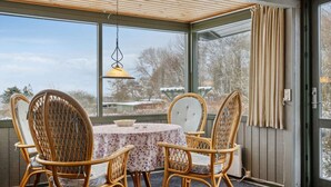 A room with a table and chairs, large windows, a hanging lamp, and a view of trees and a building outside. - 4 Star Holiday Home in Sydals (Sydals)