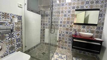Une salle de bain équipée d’une douche, de toilettes, d’un lavabo et d’un miroir.