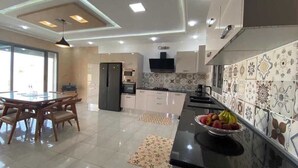 A modern kitchen with a dining area, a flat-screen TV, and patterned backsplash tiles. - Villa Laguna (Médenine)