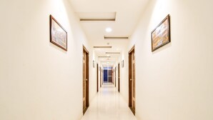 Un pasillo de hotel con cuadros enmarcados en las paredes, puertas de madera y suelo de baldosas.