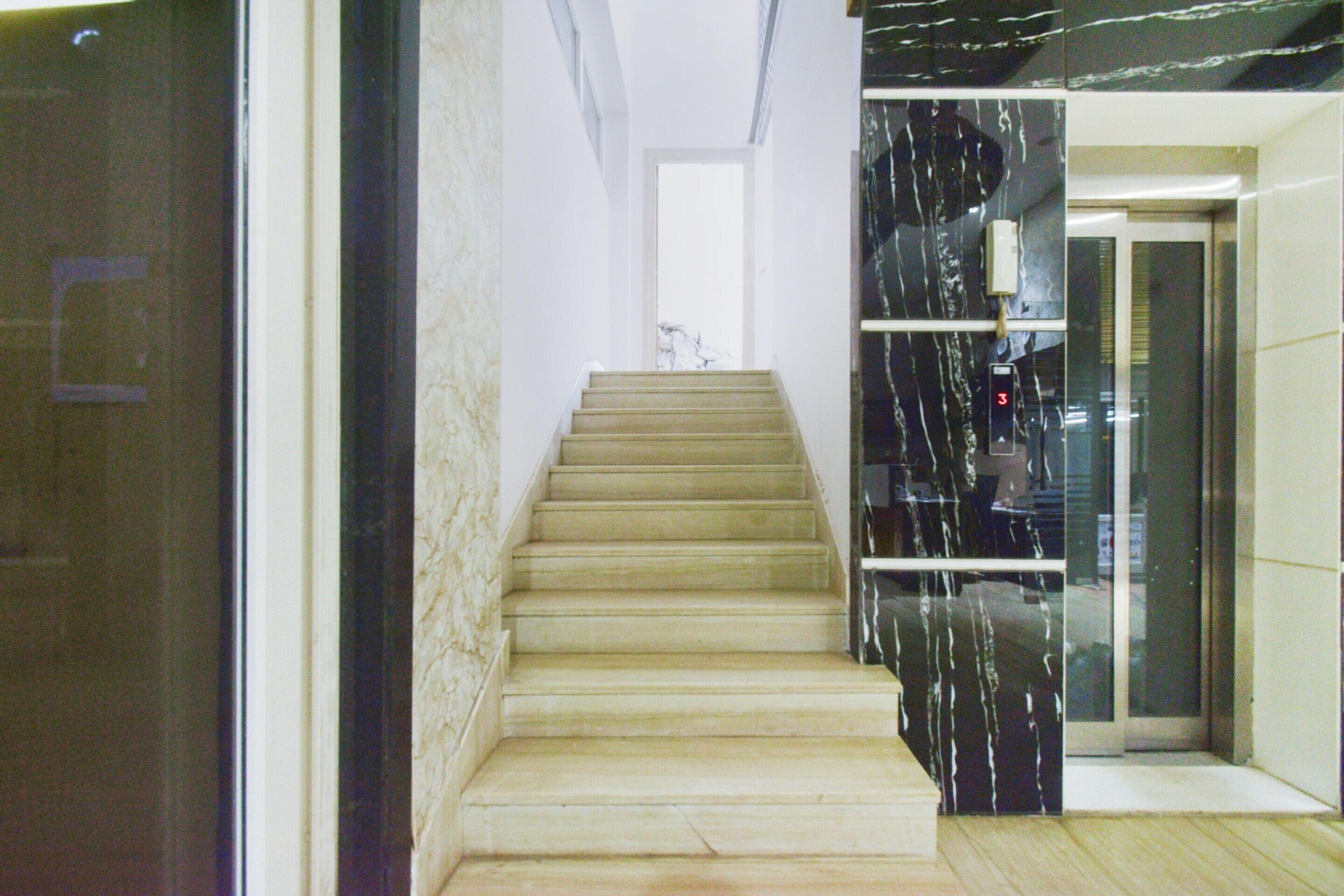 A staircase leading to an elevator in a building with marble walls.