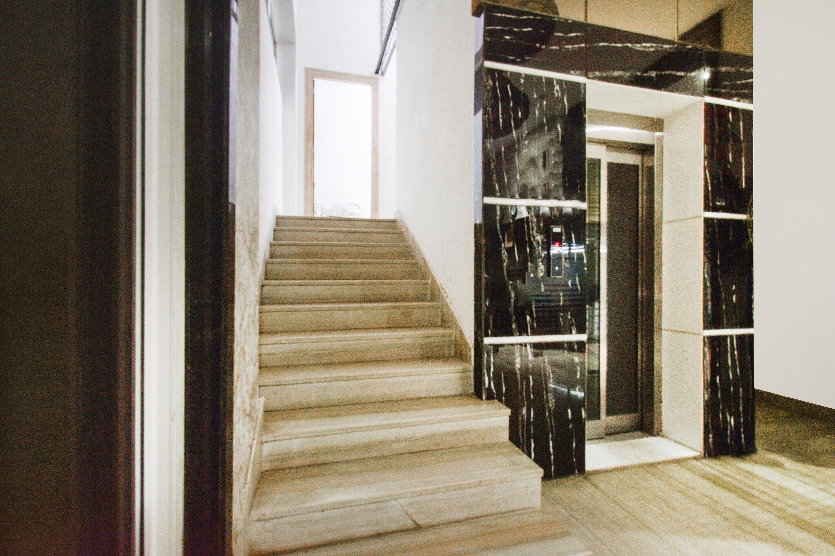 A staircase with wooden steps leading to a landing, a glass door, and a wall with a marble-like pattern.