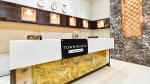 Una mesa de recepción con un letrero que dice 'TOWNHOUSE Company-Serviced', un reloj y un reloj de pared encima.