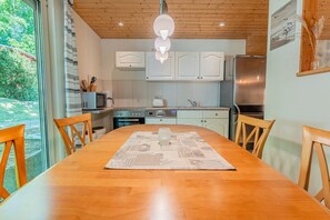 A modern kitchen with white cabinets, a stainless steel refrigerator, and a dining table with chairs.