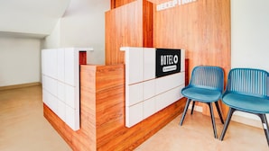 A reception desk with a wooden panel and a sign that reads 'HOTEL COMPANY SERVICES.' There are two blue chairs in front of the desk. - Deluxe Moonlit Royal Grand Suite (Aluva)