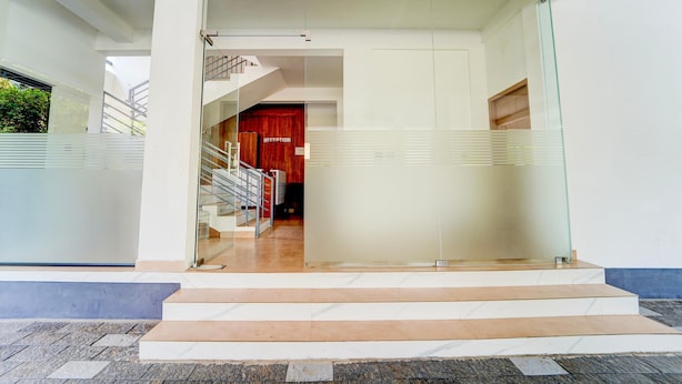 A modern building entrance with a reception area, a staircase, and a glass door. - Deluxe Moonlit Royal Grand Suite (Aluva)