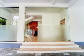 A modern building entrance with a reception area, a staircase, and a glass door. - Deluxe Moonlit Royal Grand Suite (Aluva)