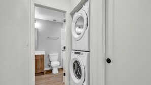 A laundry room with two stacked washing machines and a toilet. - Top Floor Walk to Beach & Casino (Penticton, BC)