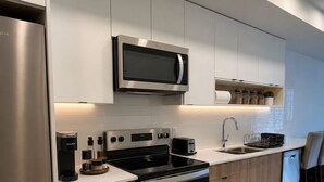A modern kitchen with stainless steel appliances, wooden cabinets, and a built-in microwave. - Top Floor Walk to Beach & Casino (Penticton, BC)