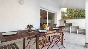 Un coin repas avec une table en bois, des chaises rouges et un saladier rempli de fruits.