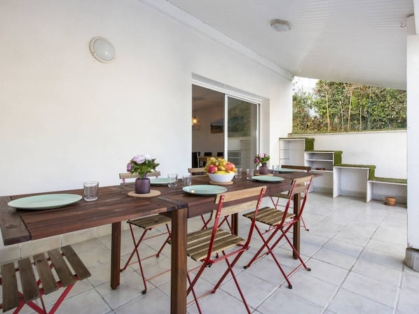 Un coin repas avec une table en bois, des chaises rouges et un saladier rempli de fruits.