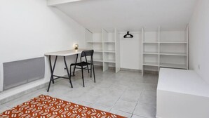 Une pièce dotée d’une lucarne, de murs blancs, d’un bureau avec une chaise et d’étagères intégrées.