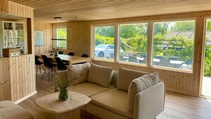 A wooden interior with a sofa, a dining table, and large windows. - 4 Star Holiday Home in Ronde (Ronde)