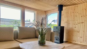 A modern interior with a wooden ceiling, a sofa, a table with a vase, and a wood-burning stove. - 4 Star Holiday Home in Ronde (Ronde)