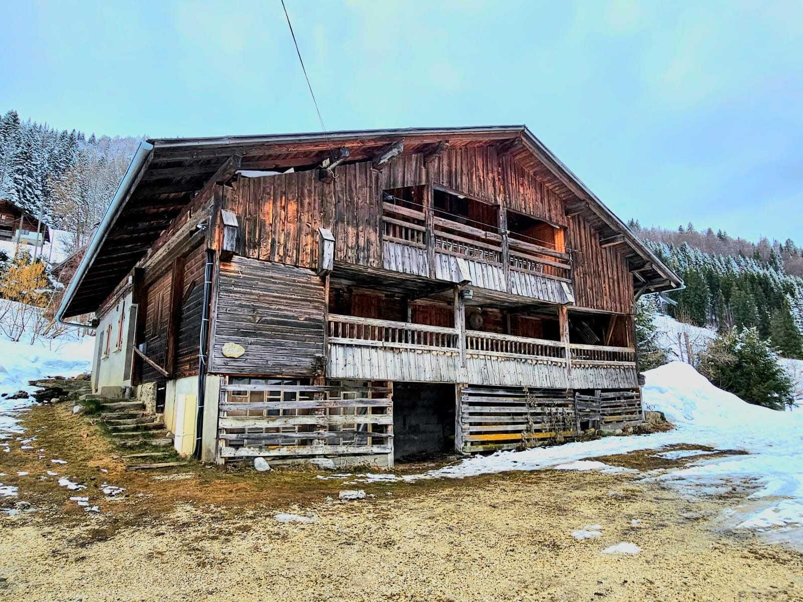 Un bâtiment rustique en bois, doté d’un balcon, entouré de neige.
