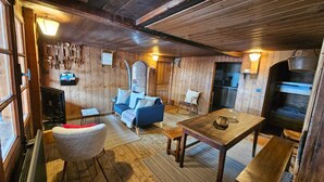 Een gezellige kamer met houten wanden, een bank, een tafel en een zitbank.