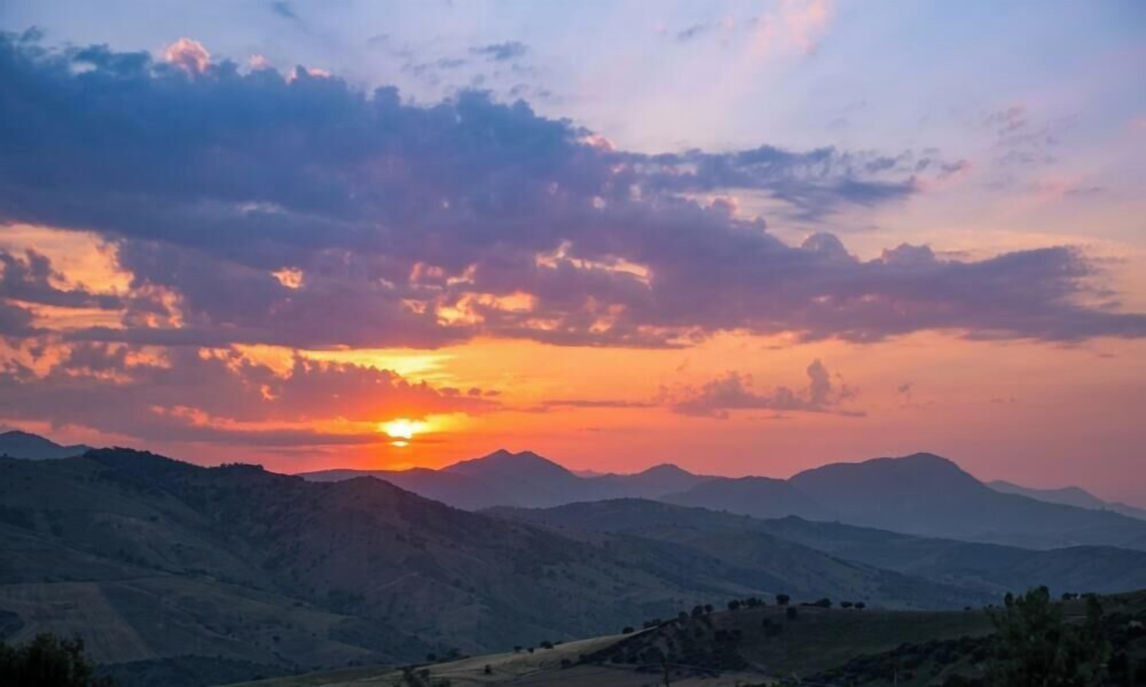 A mountainous landscape with a sunset.