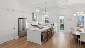 A modern kitchen with white cabinetry, a stainless steel refrigerator, and a central island with bar stools. - Close to Beach, Gated Community, Sea-Esta Villa on 30A, Golf Cart Included (Santa Rosa Beach)