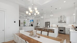A modern kitchen with white cabinetry, a wooden dining table, and pendant lighting. - Close to Beach, Gated Community, Sea-Esta Villa on 30A, Golf Cart Included (Santa Rosa Beach)