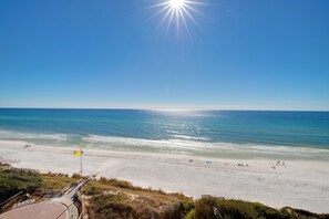 Ein Strand mit blauem Himmel, einer Flagge und einem Weg zum Wasser.