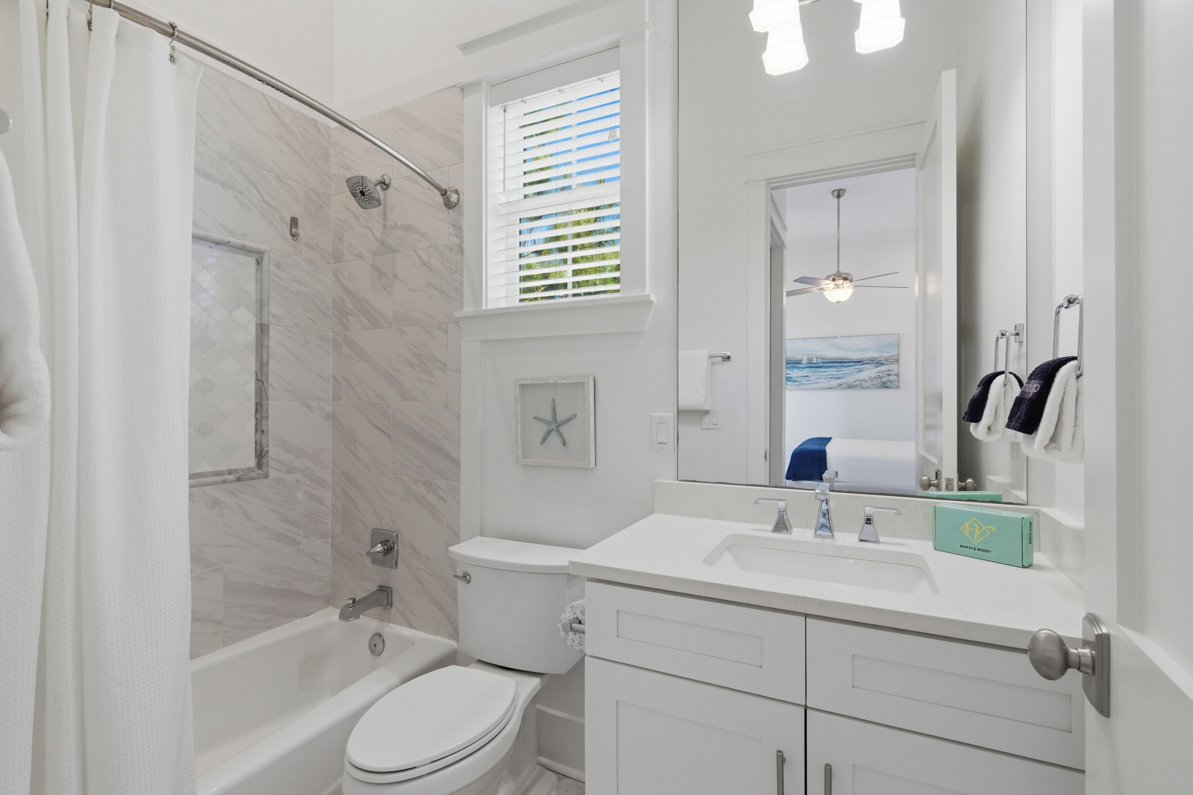 A bathroom with a shower, toilet, vanity, and a large mirror.