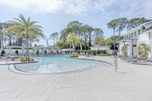 A swimming pool with lounge chairs, palm trees, and a building with a covered patio area. - Sandestin 3BDR- Sleeps 8/Golf Cart/Pet /Pool/Beach (Miramar Beach)