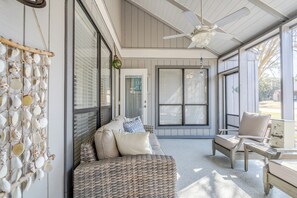 A covered porch with wicker furniture, a ceiling fan, and a wall decorated with seashells. - Sandestin 3BDR- Sleeps 8/Golf Cart/Pet /Pool/Beach (Miramar Beach)