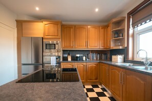 Une cuisine moderne avec des meubles en bois, des appareils en acier inoxydable et un carrelage à motifs carrés.