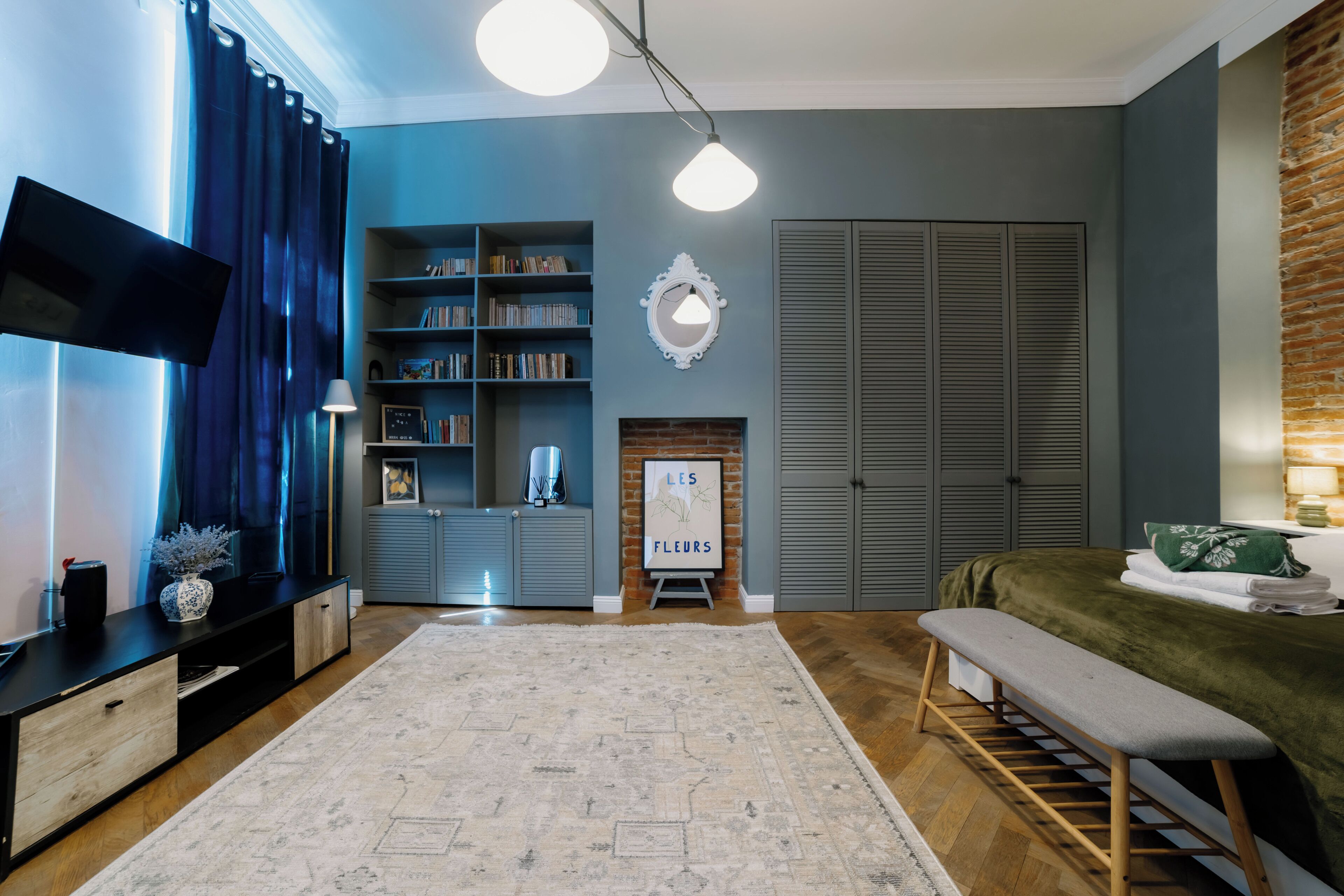 A living room with a flat-screen TV, a bookshelf, a fireplace, and a bench.