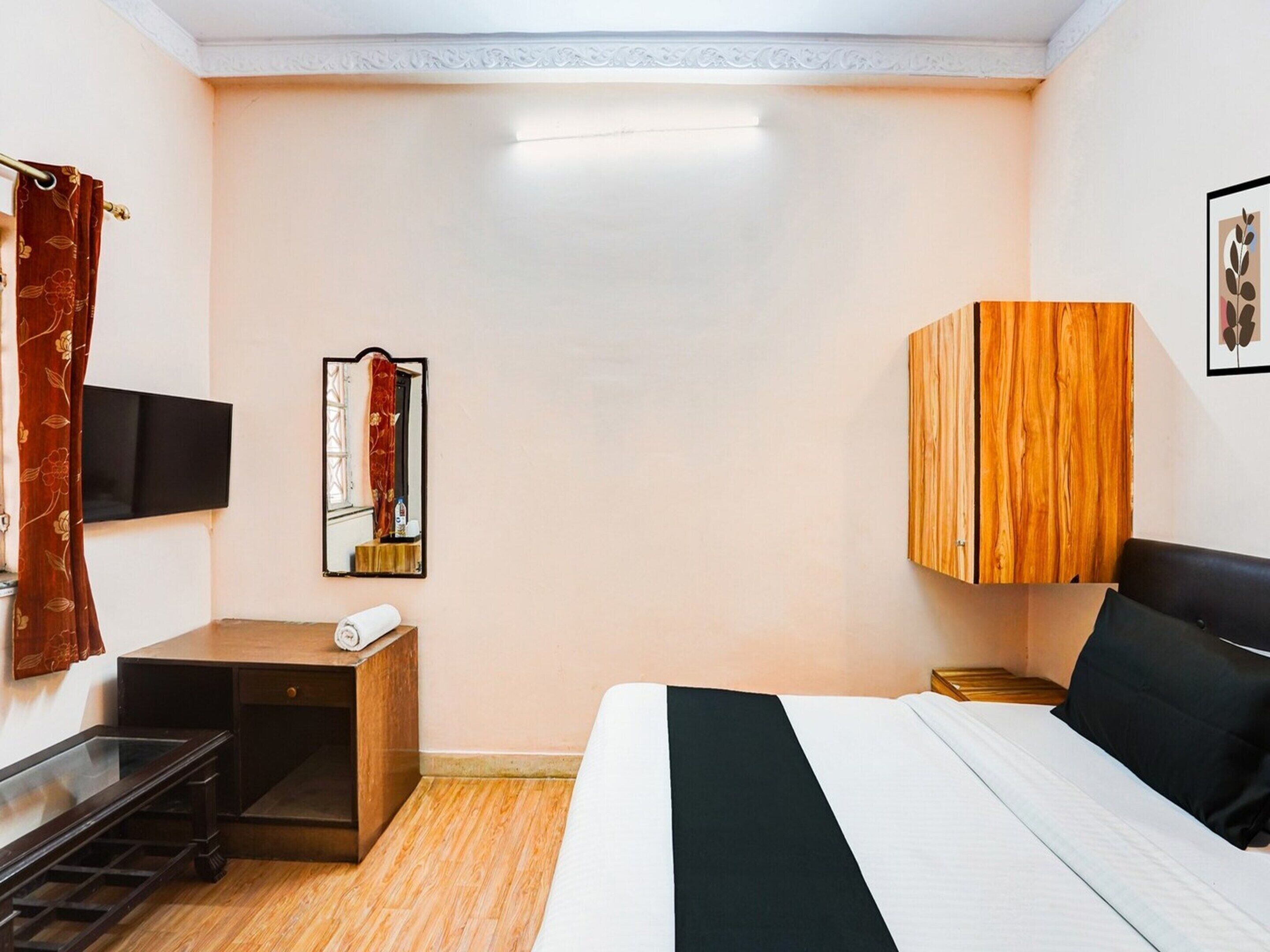 A hotel room with a bed, a desk, a TV, a mirror, and a wardrobe.