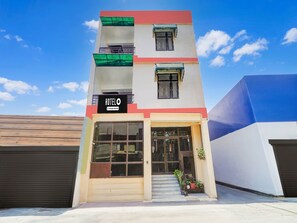 Un hôtel doté d’une façade moderne, d’une entrée bien visible et d’une enseigne indiquant qu’il s’agit d’un établissement proposant des services aux entreprises.