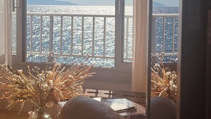 A balcony with a view of the sea and mountains, a table with a vase of dried plants, and a large stone sculpture. - Exceptional appartement with Sea view and beach private access (San Martino Di Lota)