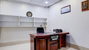Ein Hotelrezeptionstresen mit einem 'HOTELO'-Schild, einer Uhr und einem Fernseher an der Wand.