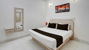 Ein Schlafzimmer mit einem Bett, einem Nachttisch, einem Spiegel, einer Wandleuchte und einem Gemälde.