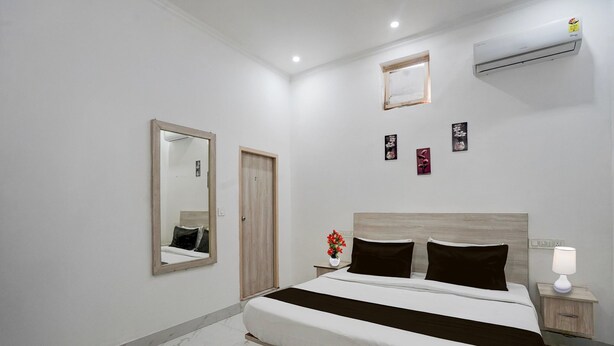 Ein modernes Schlafzimmer mit Bett, Nachttisch, Spiegel, Wandklimaanlage und kleinem Fenster.