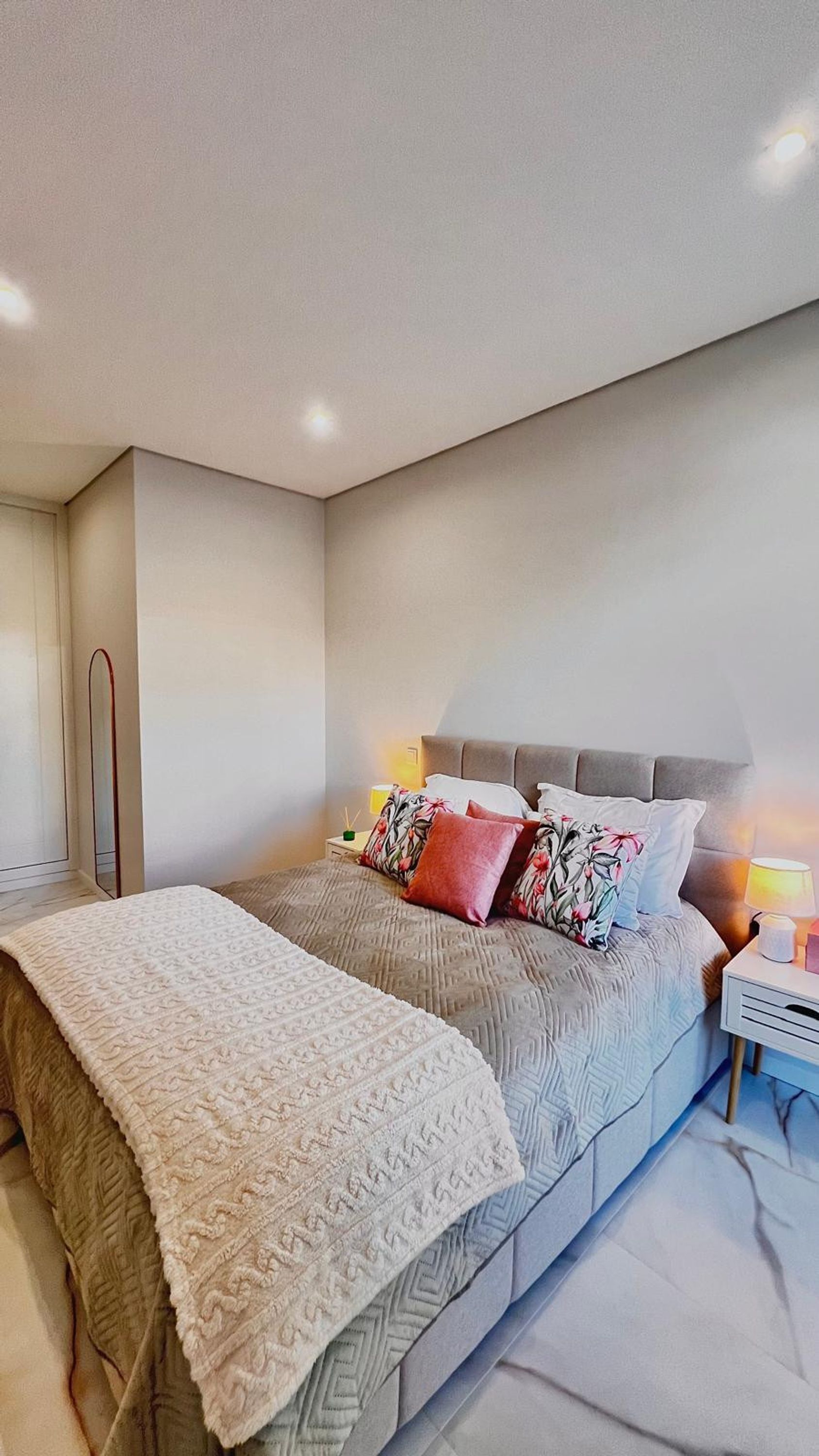 A modern bedroom with a bed, bedside lamps, and a nightstand.