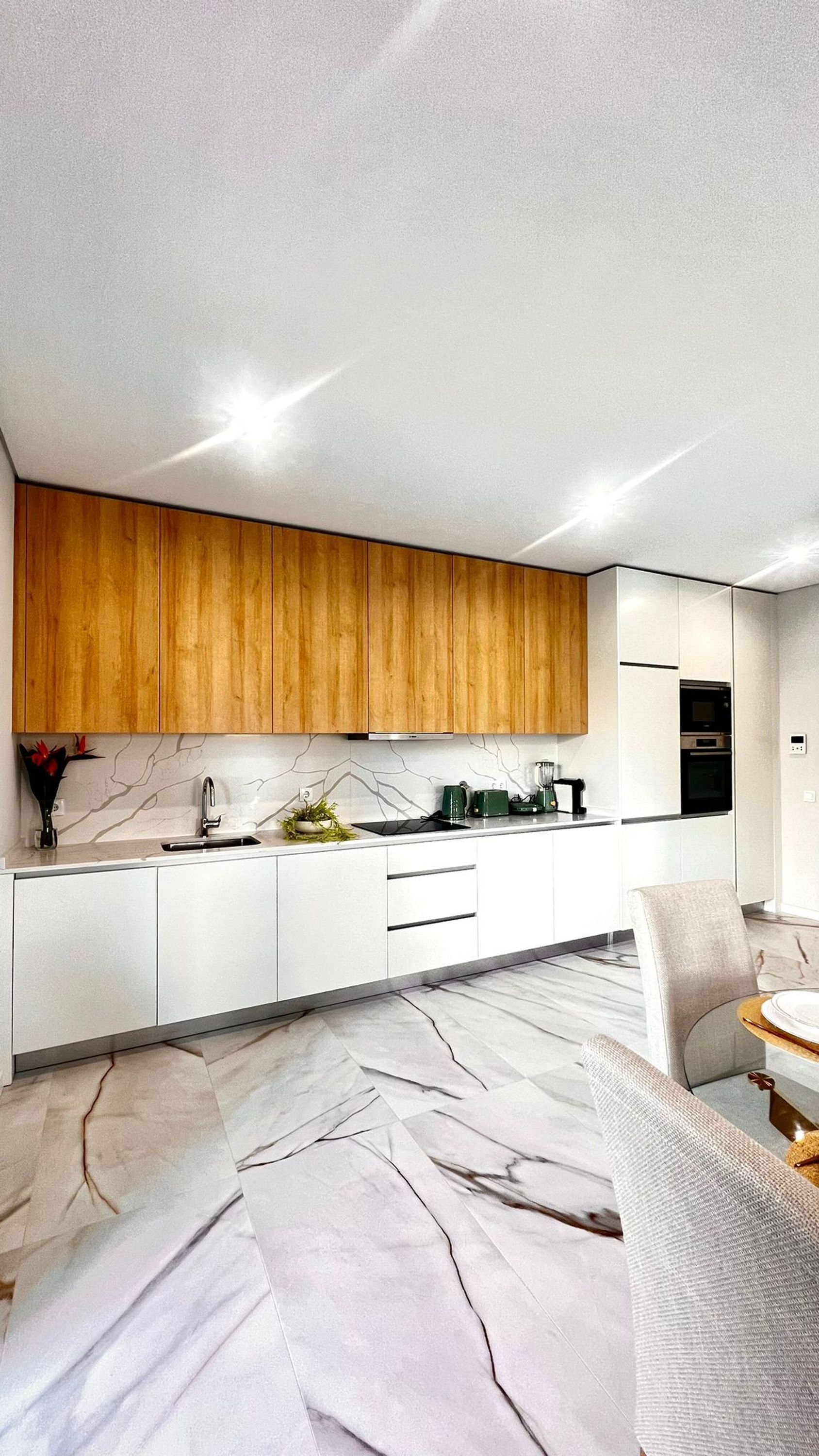A modern kitchen with wooden cabinets, a marble countertop, and built-in appliances.