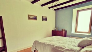 A bedroom with a bed, wooden floor, and a window.
