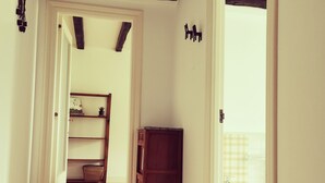 A hallway with wooden flooring, a dark wooden cabinet, and a white door leading to a bathroom.