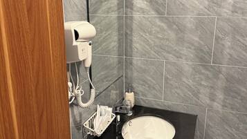 Casa de banho com lavatório preto, secador de cabelo e um frasco de sabonete líquido.