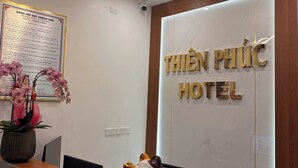 A reception desk with a sign for 'THIEN PHU C HOTEL,' a security camera, and a decorative cat figurine. - THIÊN PHÚC HOTEL (Nghia Lo)