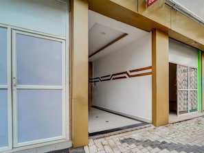 Une entrée d’immeuble avec une porte en verre, un sol carrelé et un motif décoratif sur le mur.