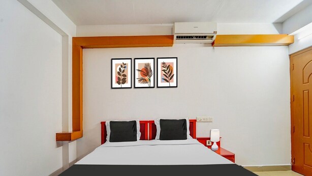 Une chambre à coucher avec un lit, une table de chevet, une lampe et trois œuvres d’art encadrées accrochées au mur.