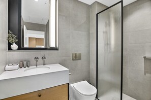 A modern bathroom with a large mirror, a sink, a toilet, and a shower enclosure. - Stylish 2-bed Apartment With Modern Amenities (Melbourne)