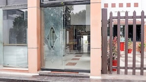 A building entrance with a glass door, a metal gate, and potted plants. - Hotel O Tyagi Road Railway (Dehradun)