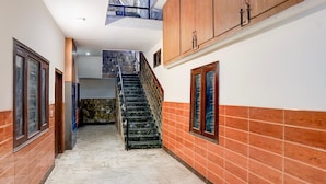 A hallway with a marble floor, wooden cabinets, and a staircase. - Hotel O Tyagi Road Railway (Dehradun)